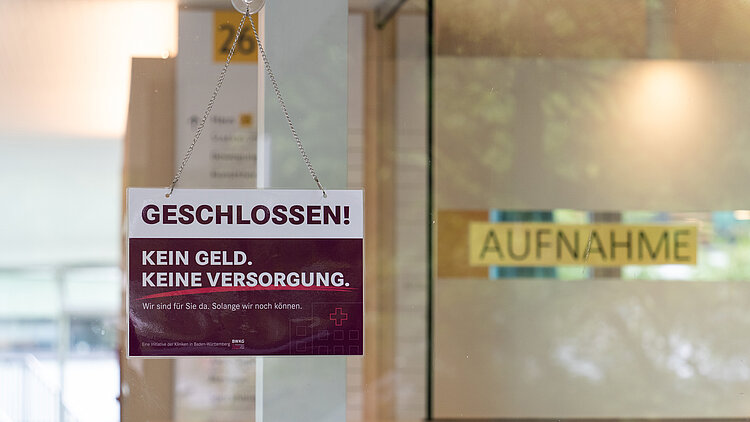 An einer Tür hängt ein Geschlossen-Schild. Im Hintergrund ist verschwommen das Schild "Aufnahme" zu sehen.